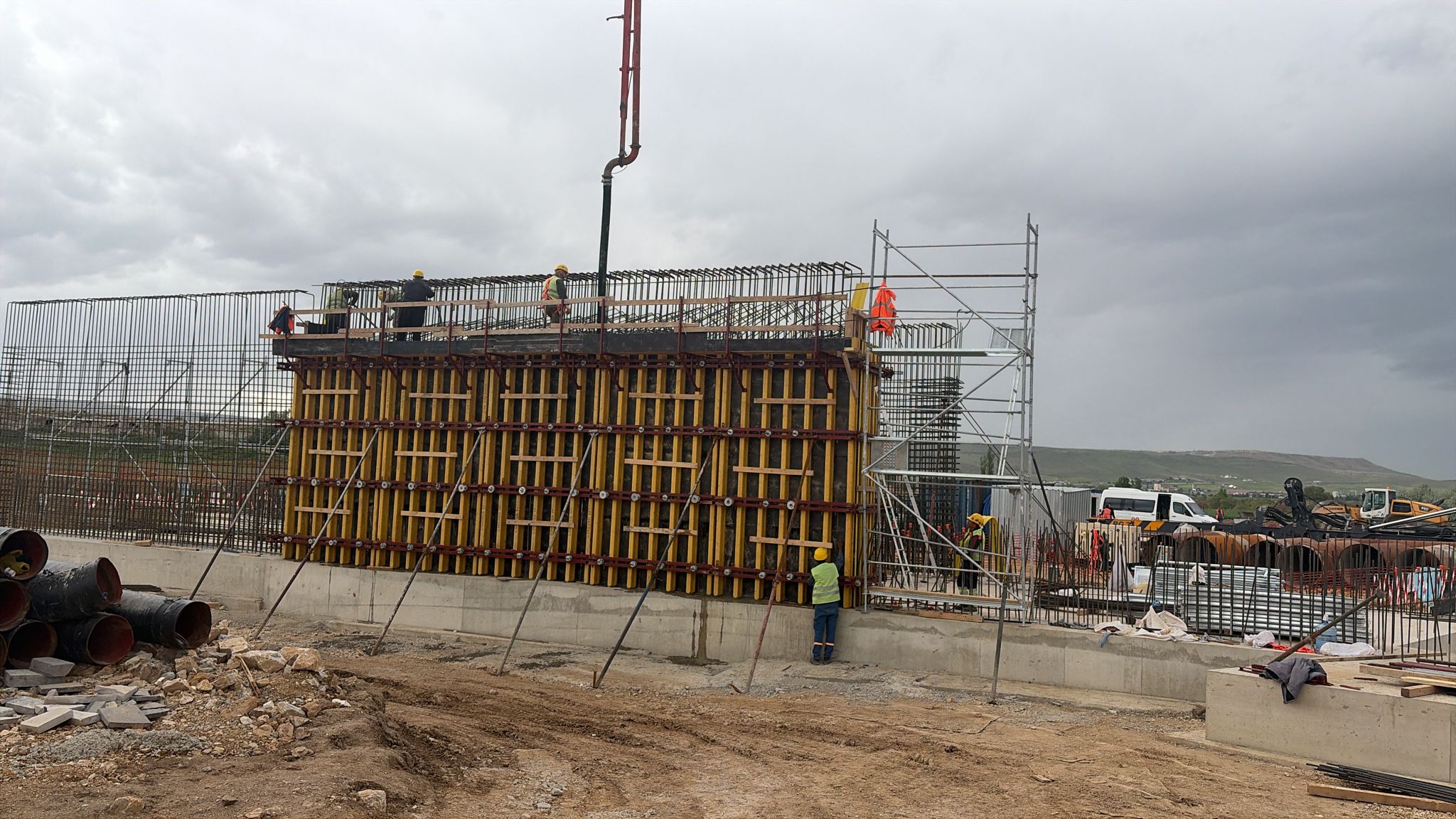 Sarı baretli saha ekibiyle perde kalıbı ve beton dökümü